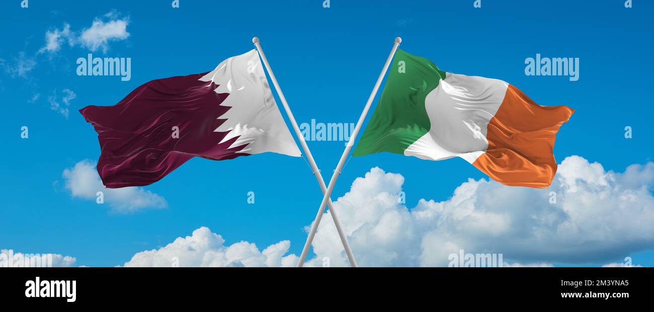 two crossed flags Ireland and Qatar waving in wind at cloudy sky ...