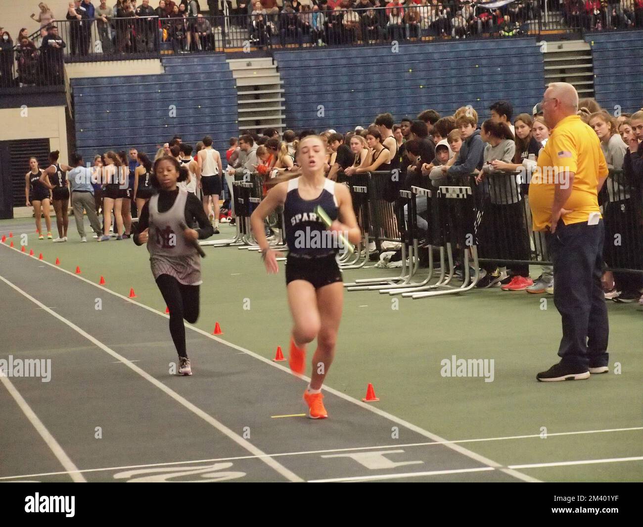 High school girls running on an indoor track during competition Stock Photo