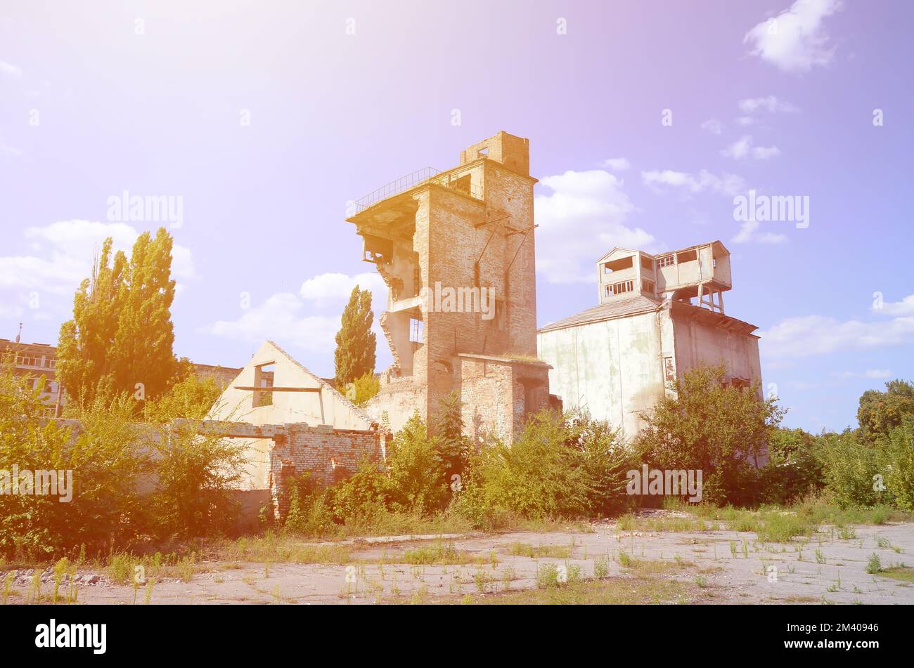 Collapsed industrial multistorey building in daytime. Disaster scene full of debris, broken bricks and damaged non residental house. Concept of war action aftermath or building demolition Stock Photo