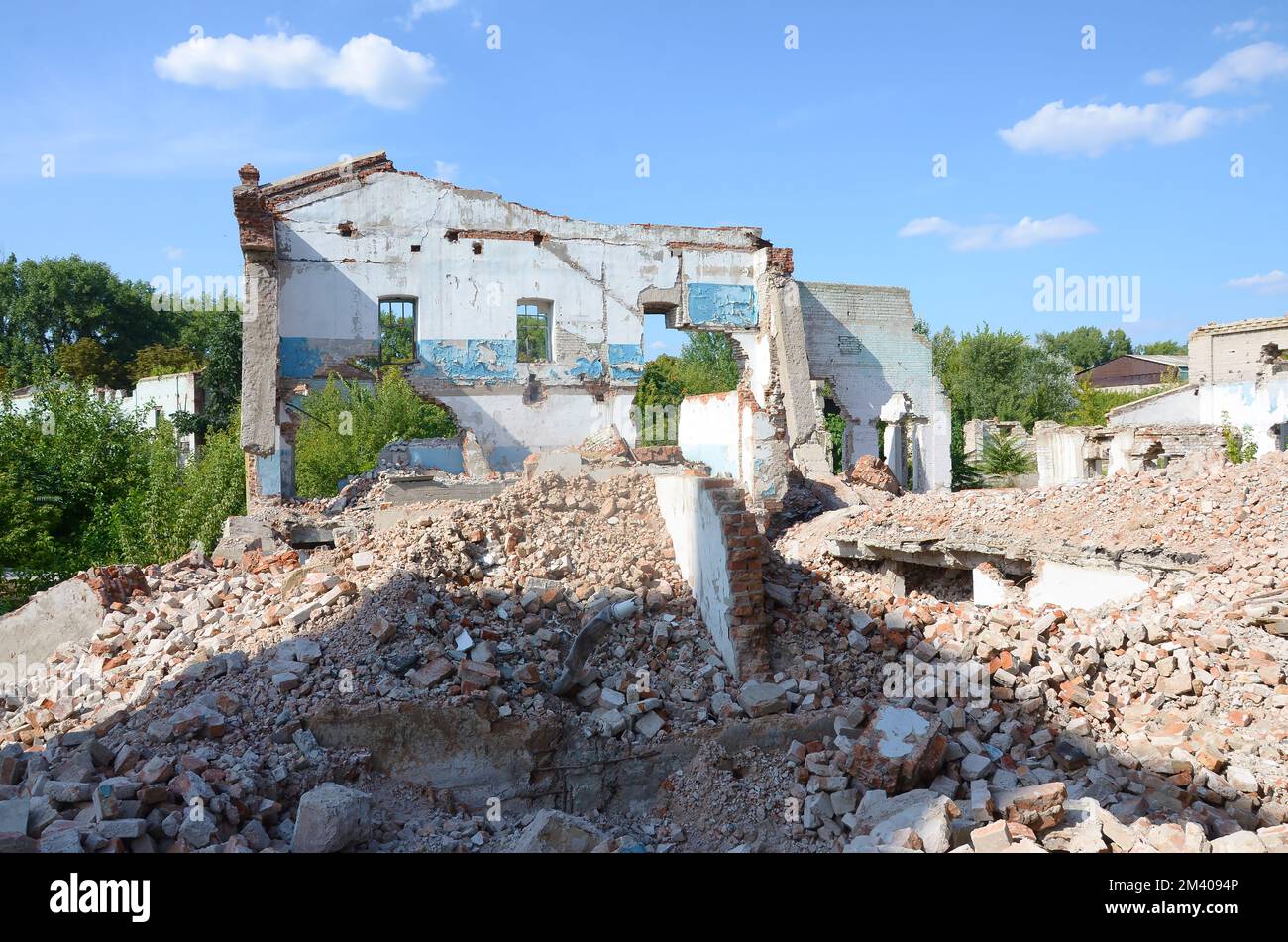 Collapsed industrial multistorey building in daytime. Disaster scene full of debris, broken bricks and damaged non residental house. Concept of war action aftermath or building demolition Stock Photo