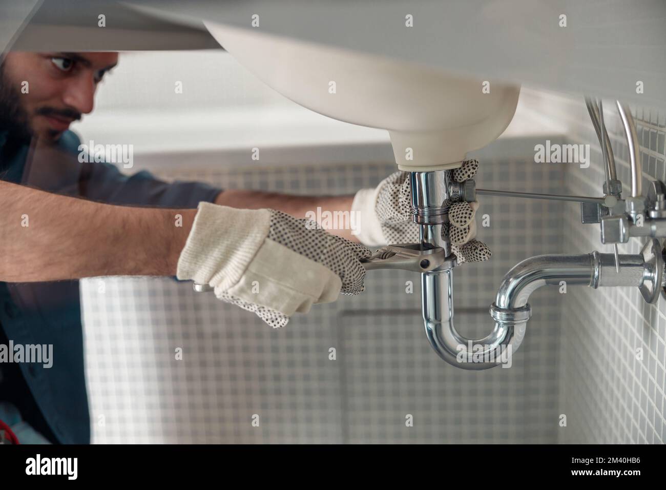 Close up of indian plumber is repairing faucet of a sink at bathroom