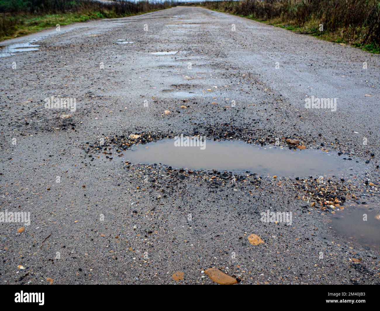 Pothole on a paved road on a rainy winter day. Concept of risk and