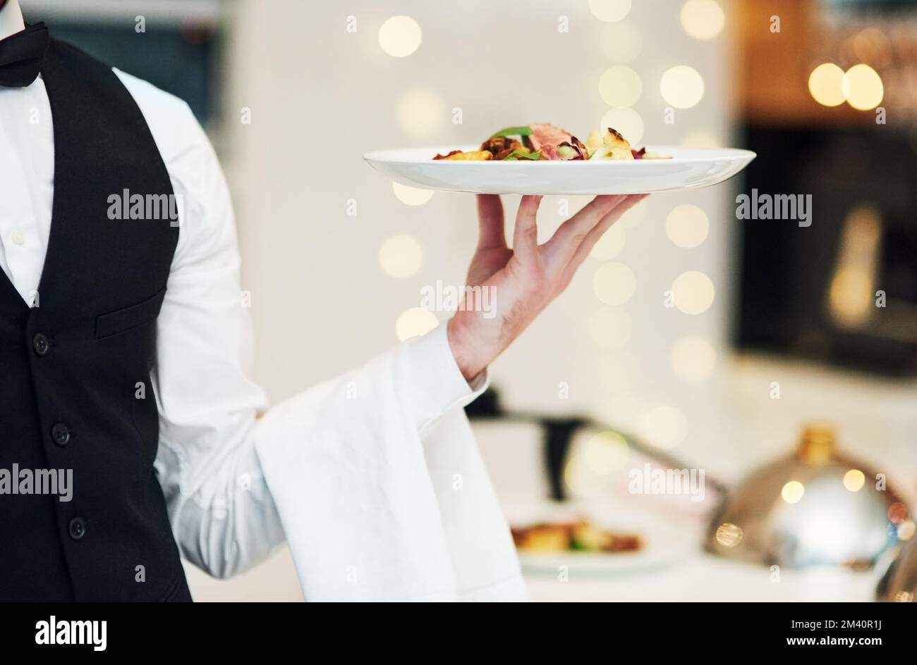 He serves with class. an unrecognizable young waiter holding a plate of