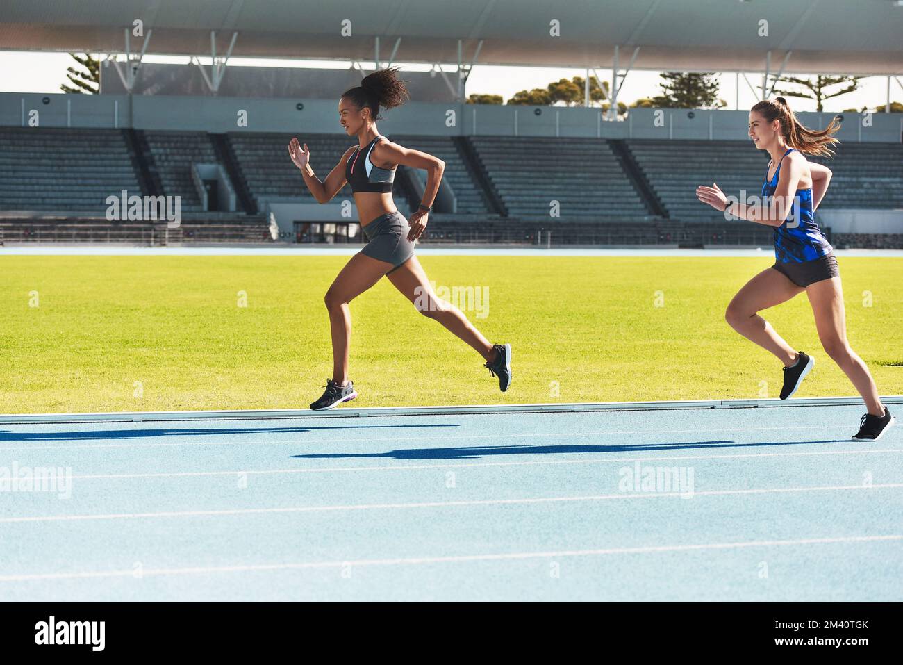 Catching up. Full length shot of two attractive young female athletes running along the track. Stock Photo