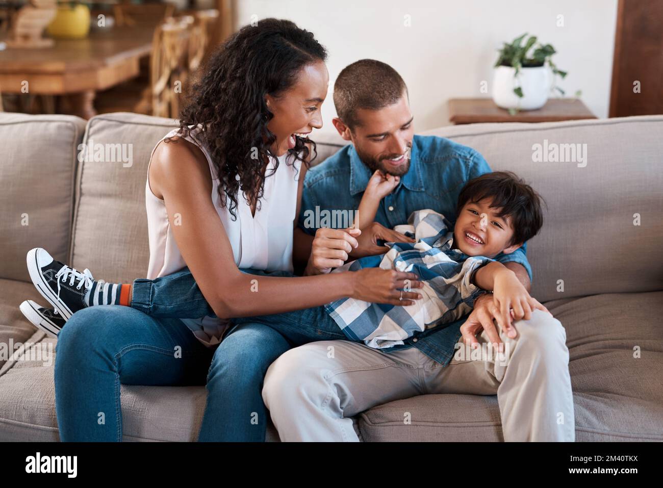 We love seeing him happy. a young boy being tickled by his parents. Stock Photo