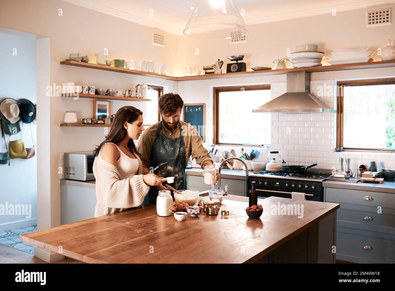 Bake your home a happy place. a young couple using a digital tablet while preparing breakfast at home. Stock Photo