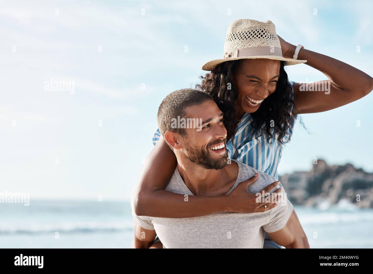 Love puts bliss into the world. a young man piggybacking his girlfriend at the beach. Stock Photo