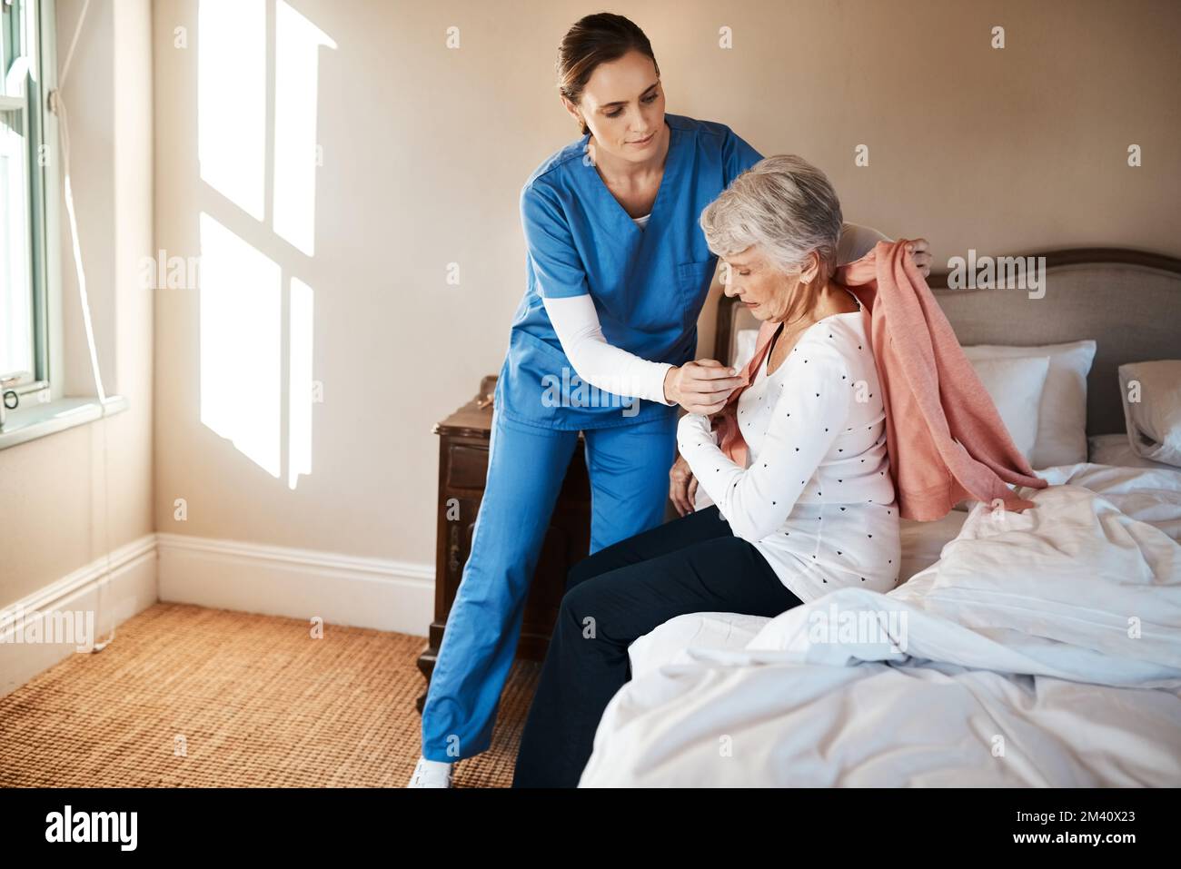 One day well all need a bit of extra help. a young nurse helping a senior woman get dressed in her bedroom at a nursing home. Stock Photo