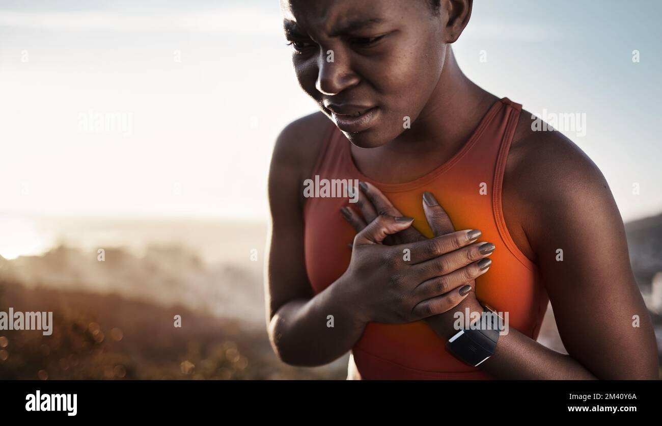 Heart pain, fitness and black woman with an injury from cardio, running and nature workout in Germany. Asthma, health and African runner with heart Stock Photo