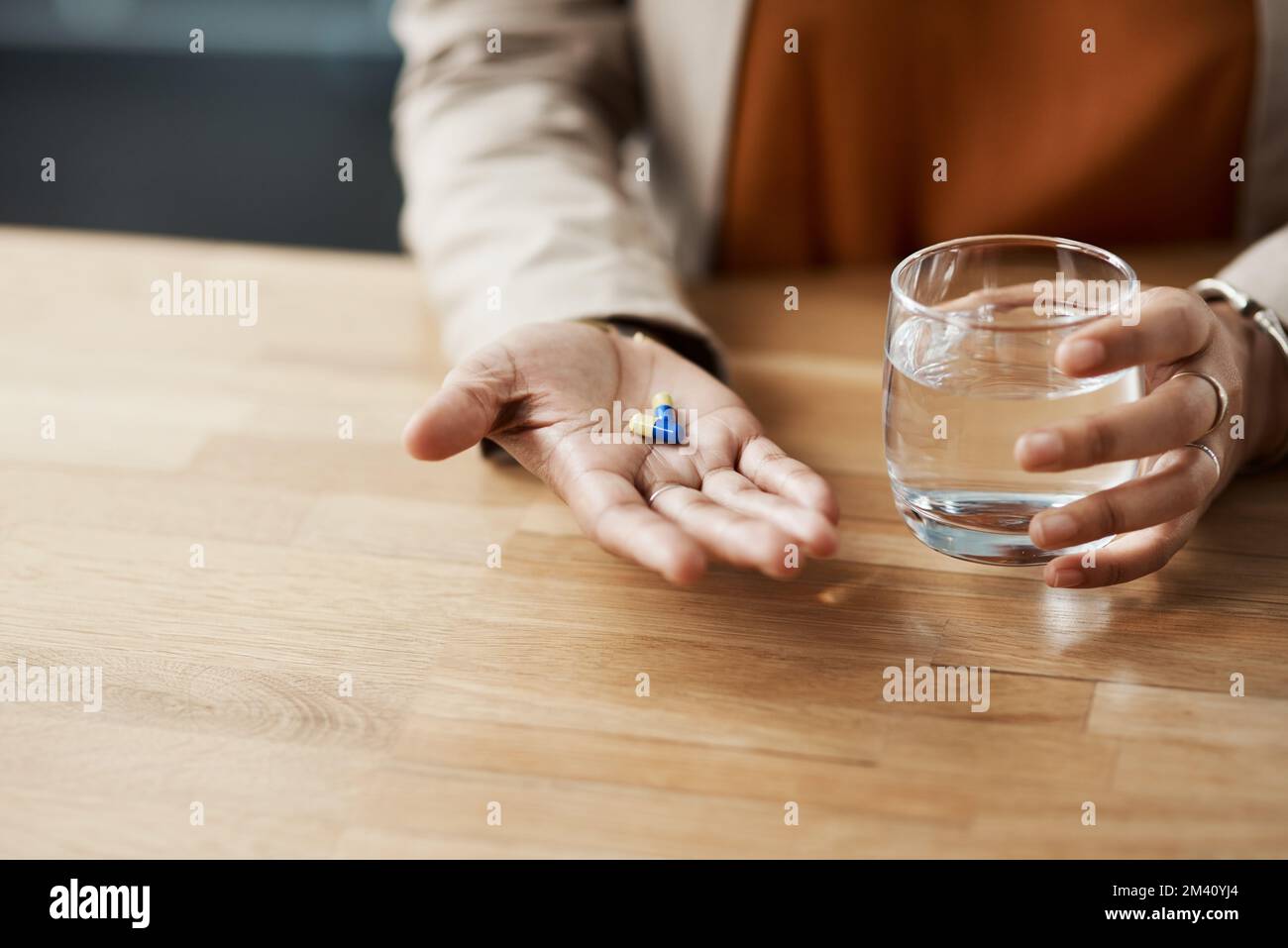 I really need these pills. an unrecognizable businesswoman taking pills with a glass of water while in her office. Stock Photo