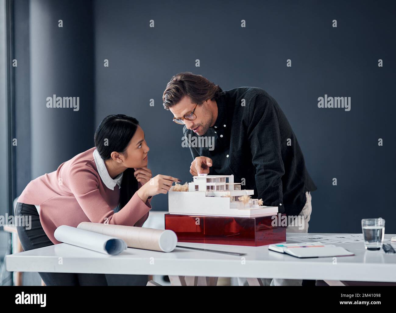 Things are coming together perfectly. two young architects working together on a scale model of a modern house in their office. Stock Photo
