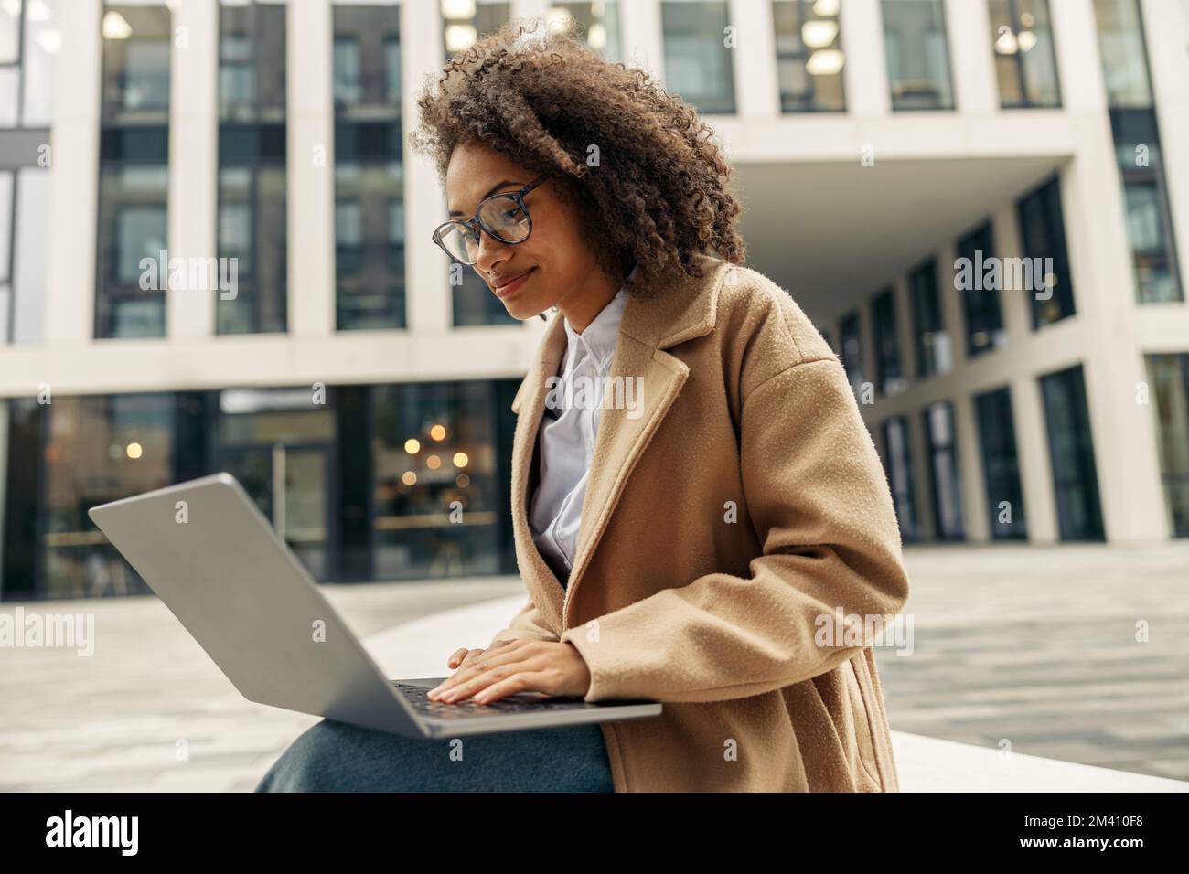 Happy african business woman working laptop while sitting outside on ...