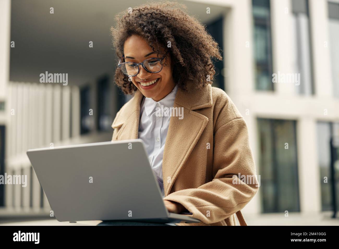 Happy african business woman working laptop while sitting outside on ...