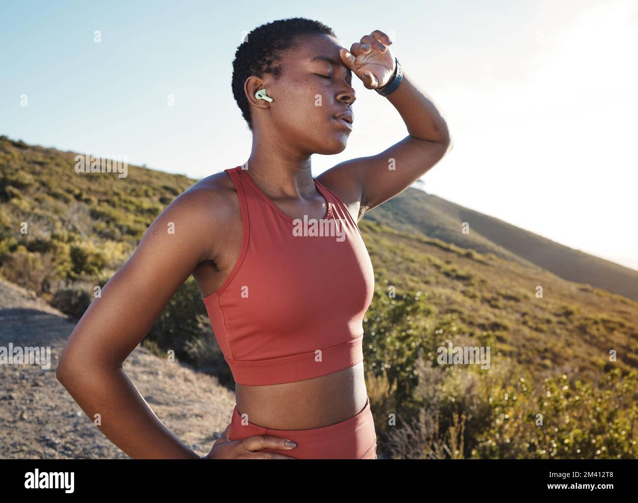 Fitness, black woman and tired from mountain running, cardio workout and outdoor exercise. Sweating, breathing and body fatigue of runner in nature Stock Photo