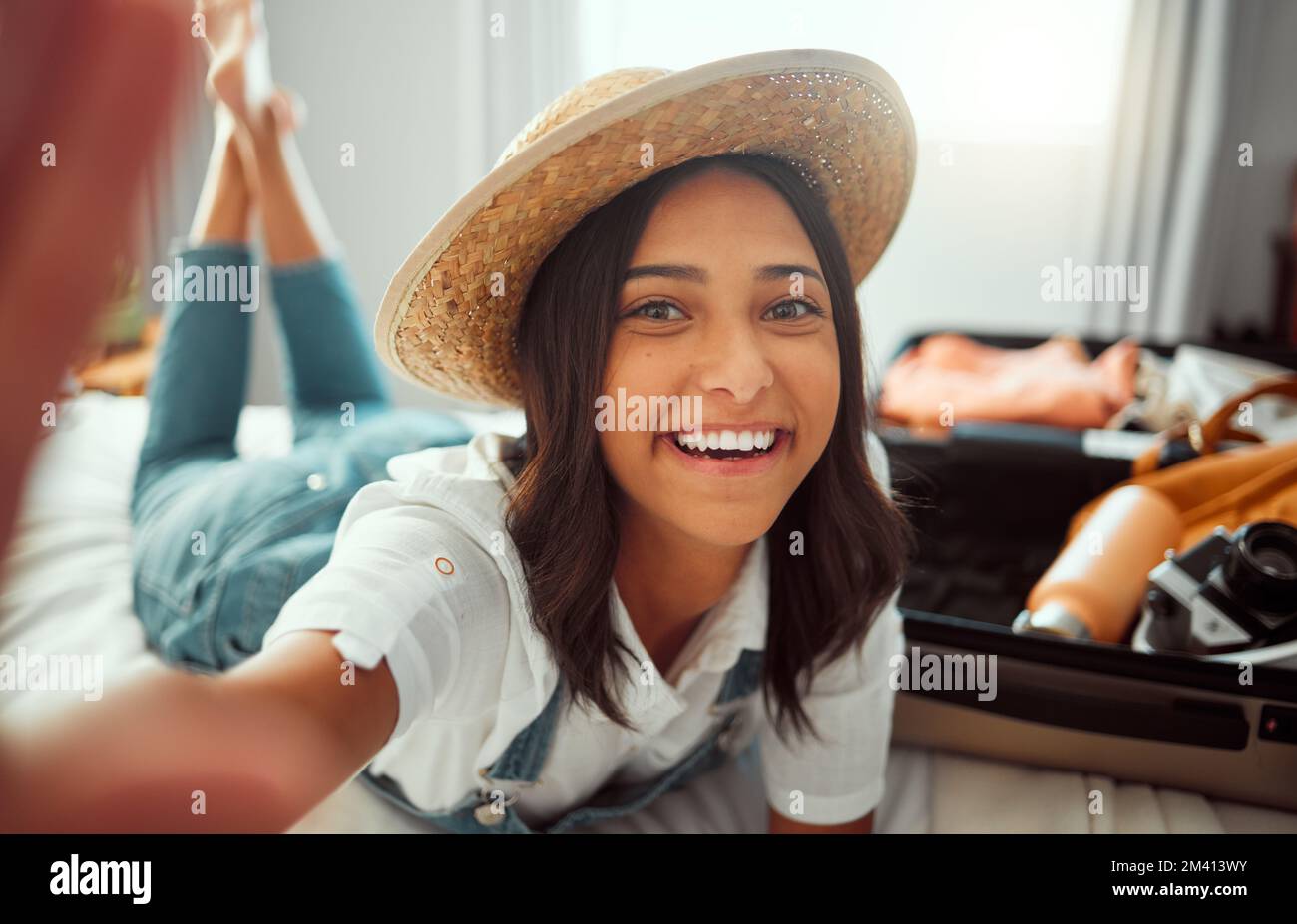 Face, travel selfie and woman packing suitcase getting ready for vacation or holiday. Portrait, relax and happy female taking pictures in hat while Stock Photo