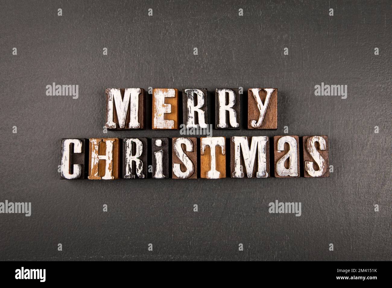 Merry Christmas concept. Alphabet wooden blocks on a dark board. Stock Photo