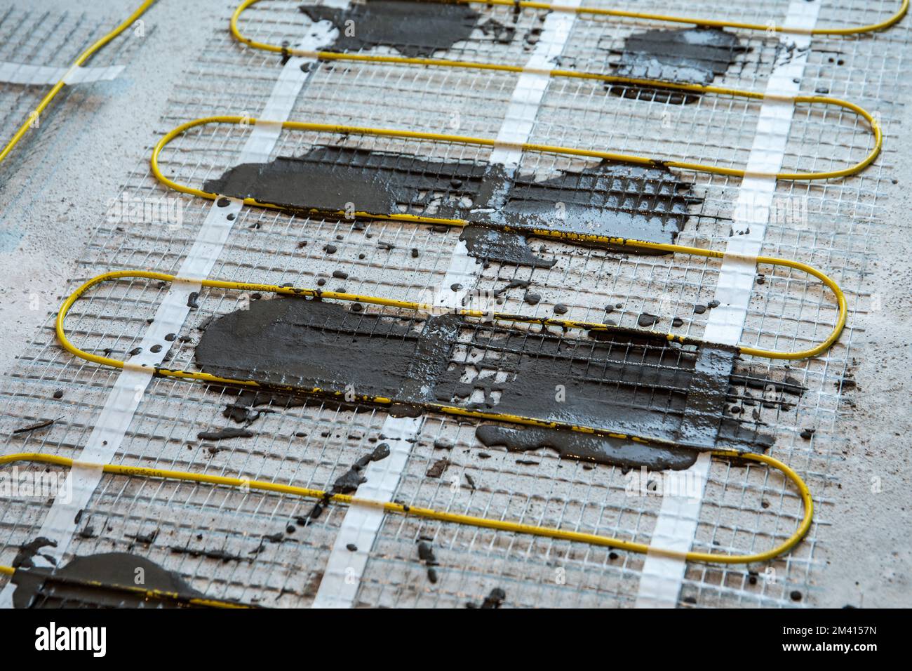 Electric warm floor laying. Cable and fiberglass mesh with tile adhesive. Stock Photo