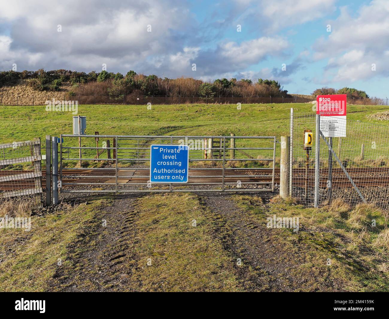 A private level crossing on the East Coast Mainline towards Fields on the Arbroath to Easthaven Footpath with a Telephone and warning signs. Stock Photo