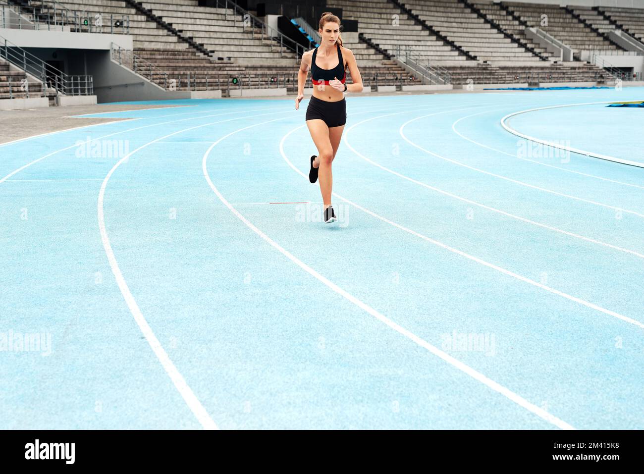 Sometimes all you need is a good, long run. Full length shot of an attractive young athlete running a track field alone during a workout session Stock Photo