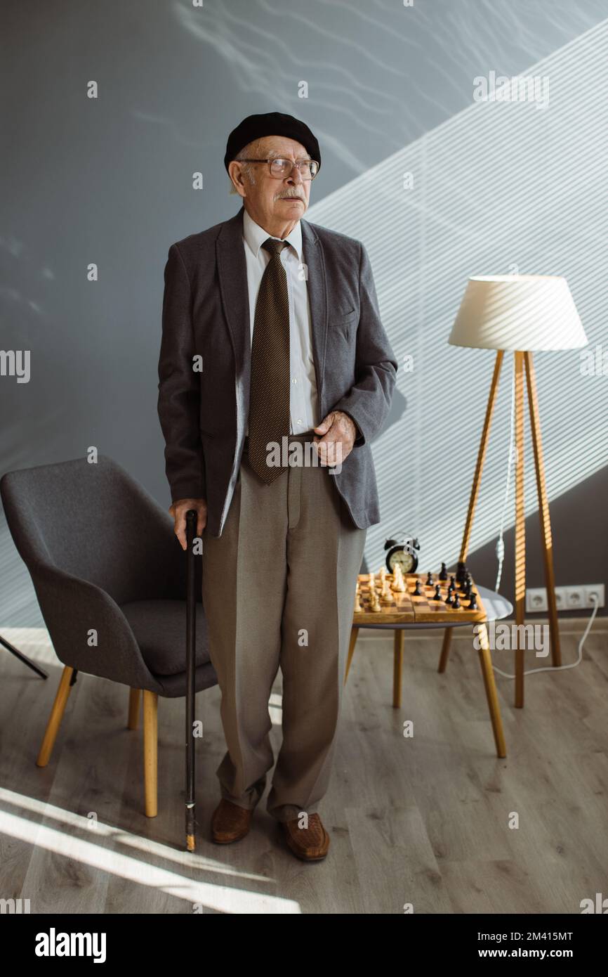 Portrait of a gray-haired old man with a stick in his hands. Stock Photo