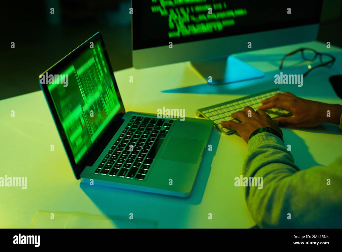 Getting up to no good in the dark. an unrecognizable hacker cracking a computer code in the dark. Stock Photo