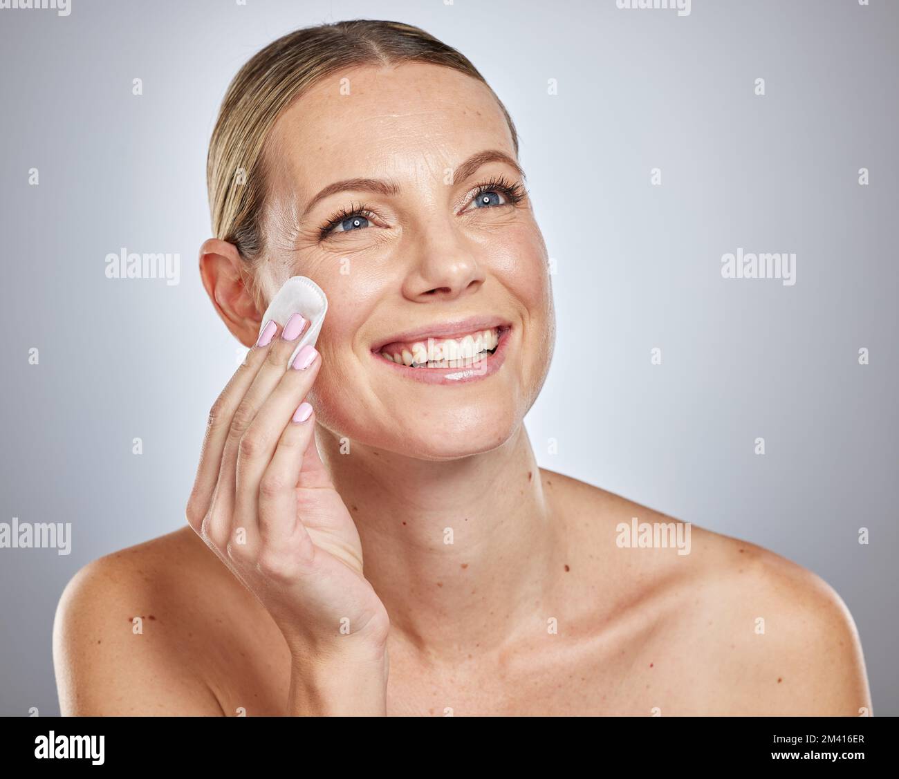 Woman, beauty studio and skincare with cotton pad, cleaning and dermatology health by backdrop. Model, skin wellness and cosmetic clean for glow Stock Photo