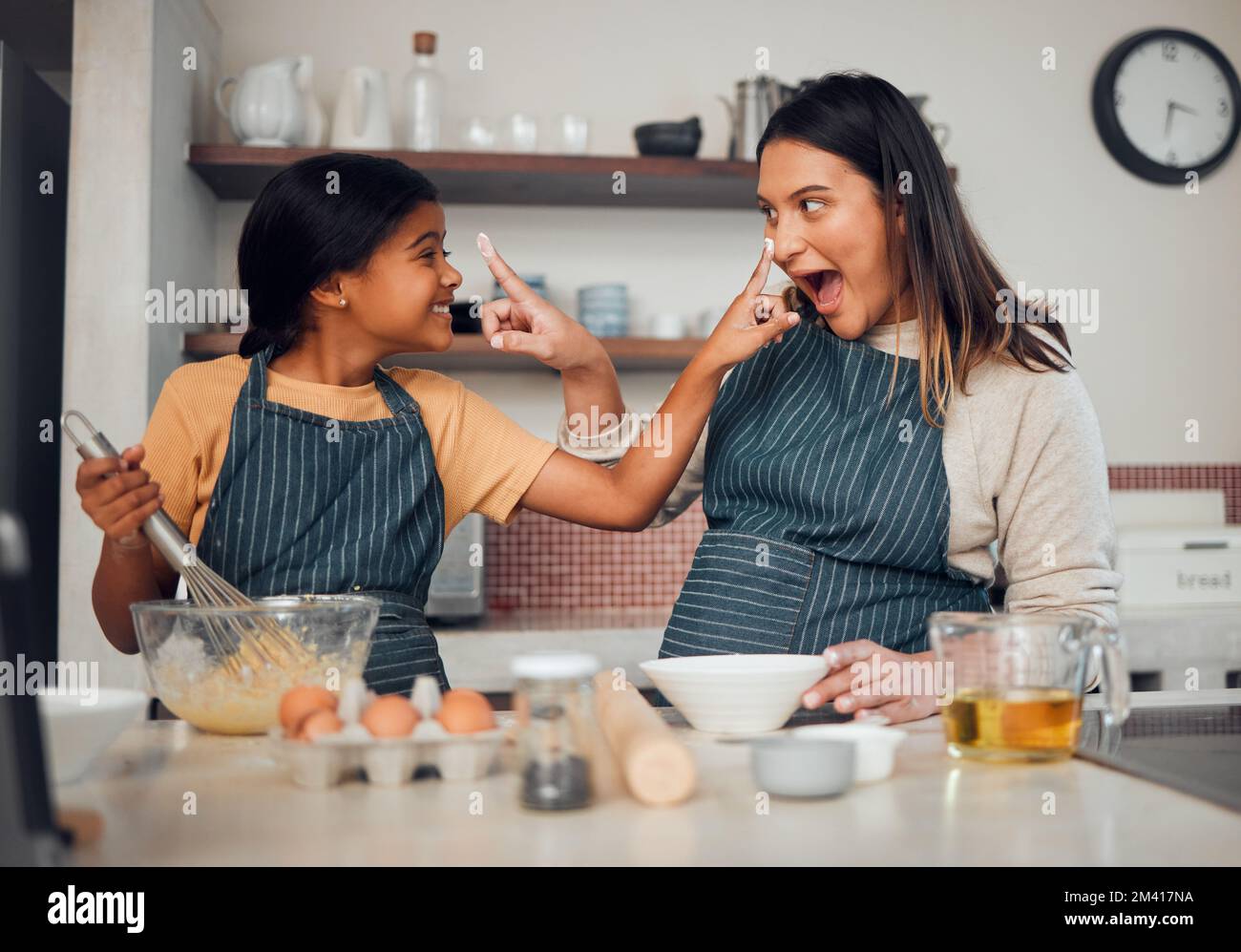 Baking, family and children with a mother and daughter learning hot to bake while being playful in the kitchen. Fun, kids and food with a girl and Stock Photo