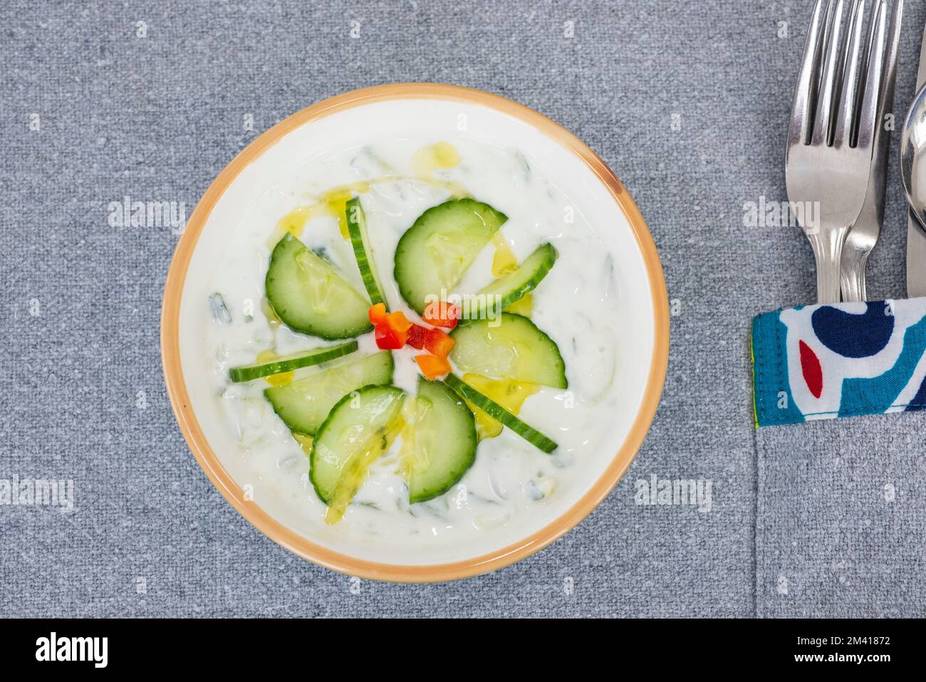 Tzatziki a la carte appetiser meal dip in a white bowl dish with fresh cucumber and cutlery Stock Photo