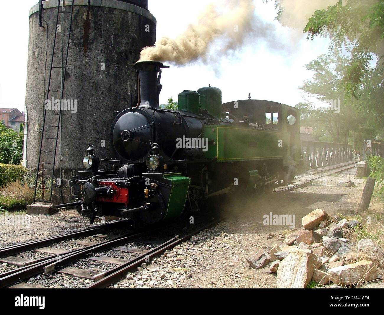 Locomotive stops on the track next to the water tower to refuel the boiler tanks Stock Photo