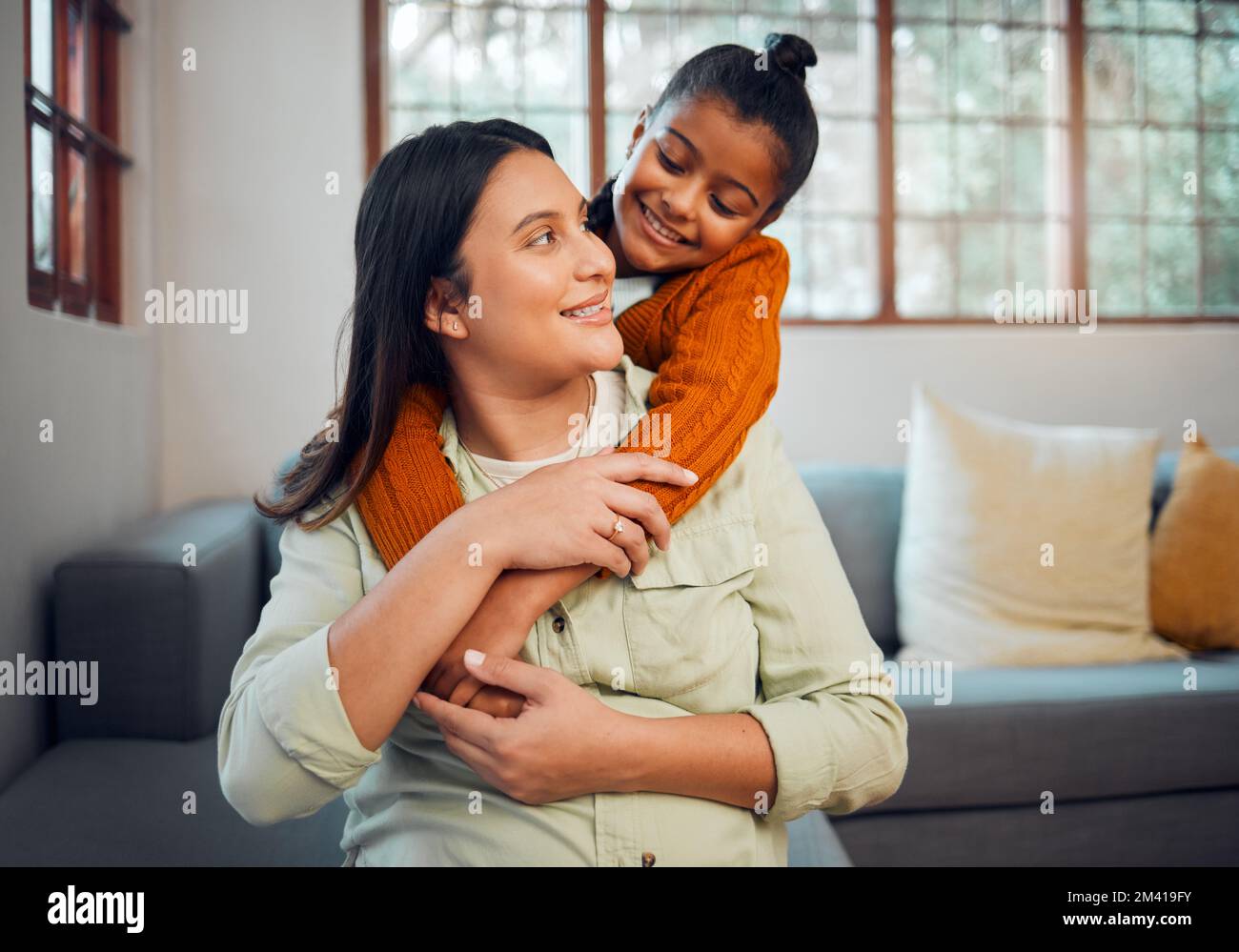 Mom, girl and hug by sofa in living room, family home and happy together for love, bonding and care. Happiness, mother and daughter with embrace Stock Photo