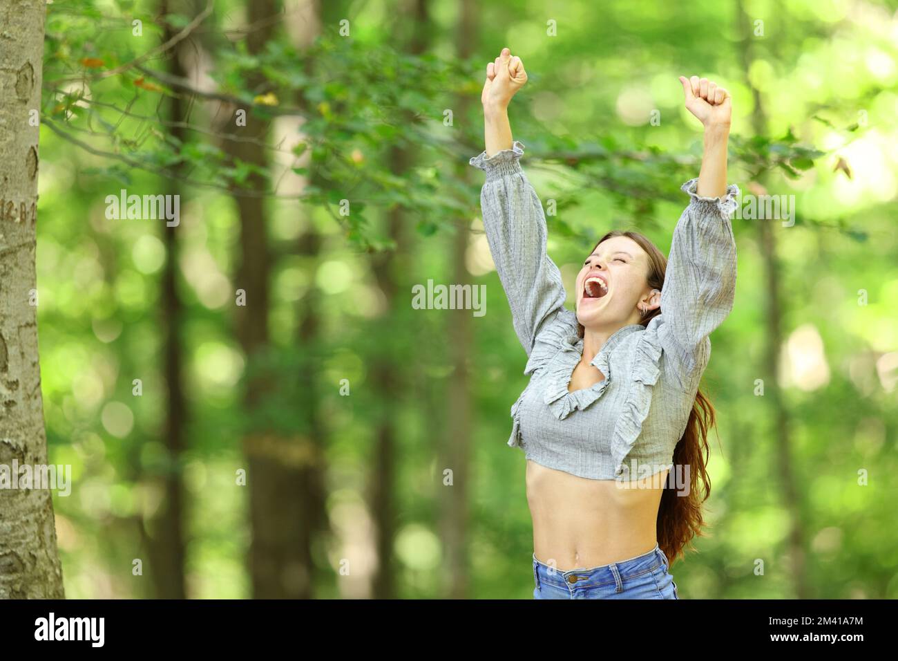 Excited woman raising arms standing in a park or forest Stock Photo - Alamy