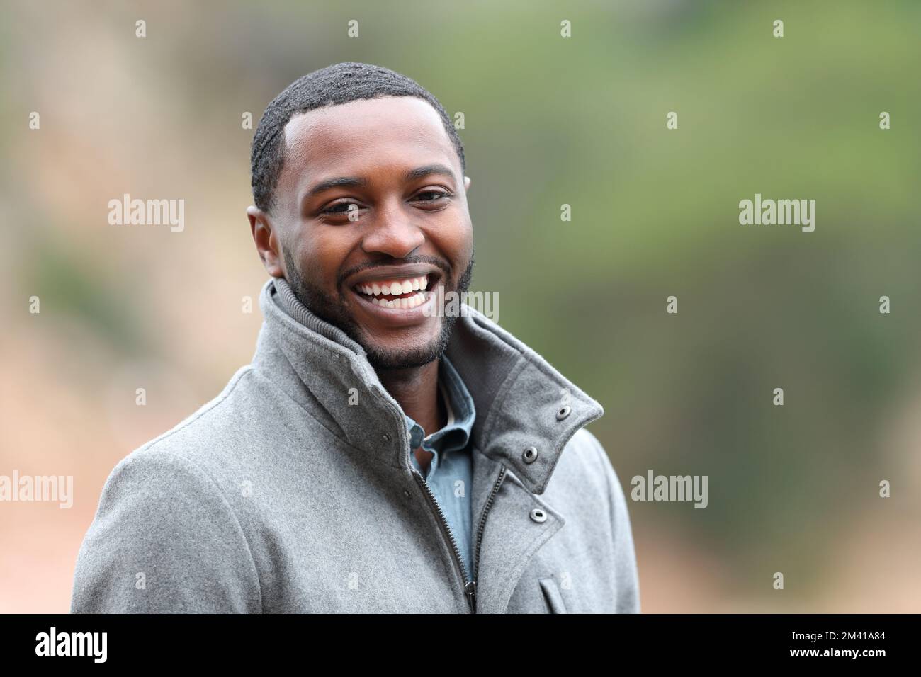 Portrait of a happy black man looking at you in winter in a park Stock Photo