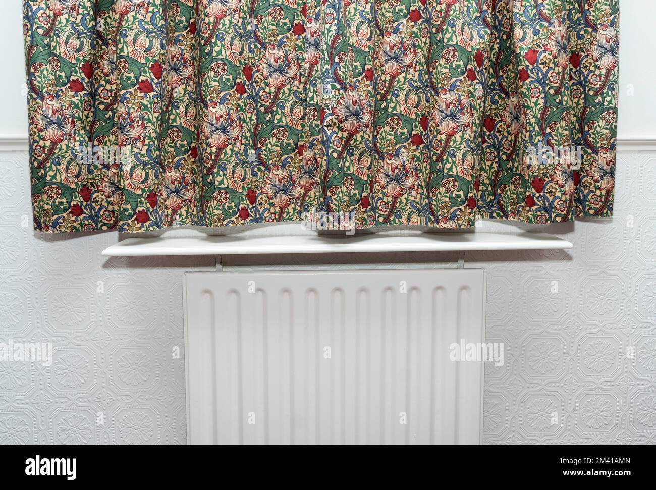 Energy saving concept a radiator shelf below a window with curtains