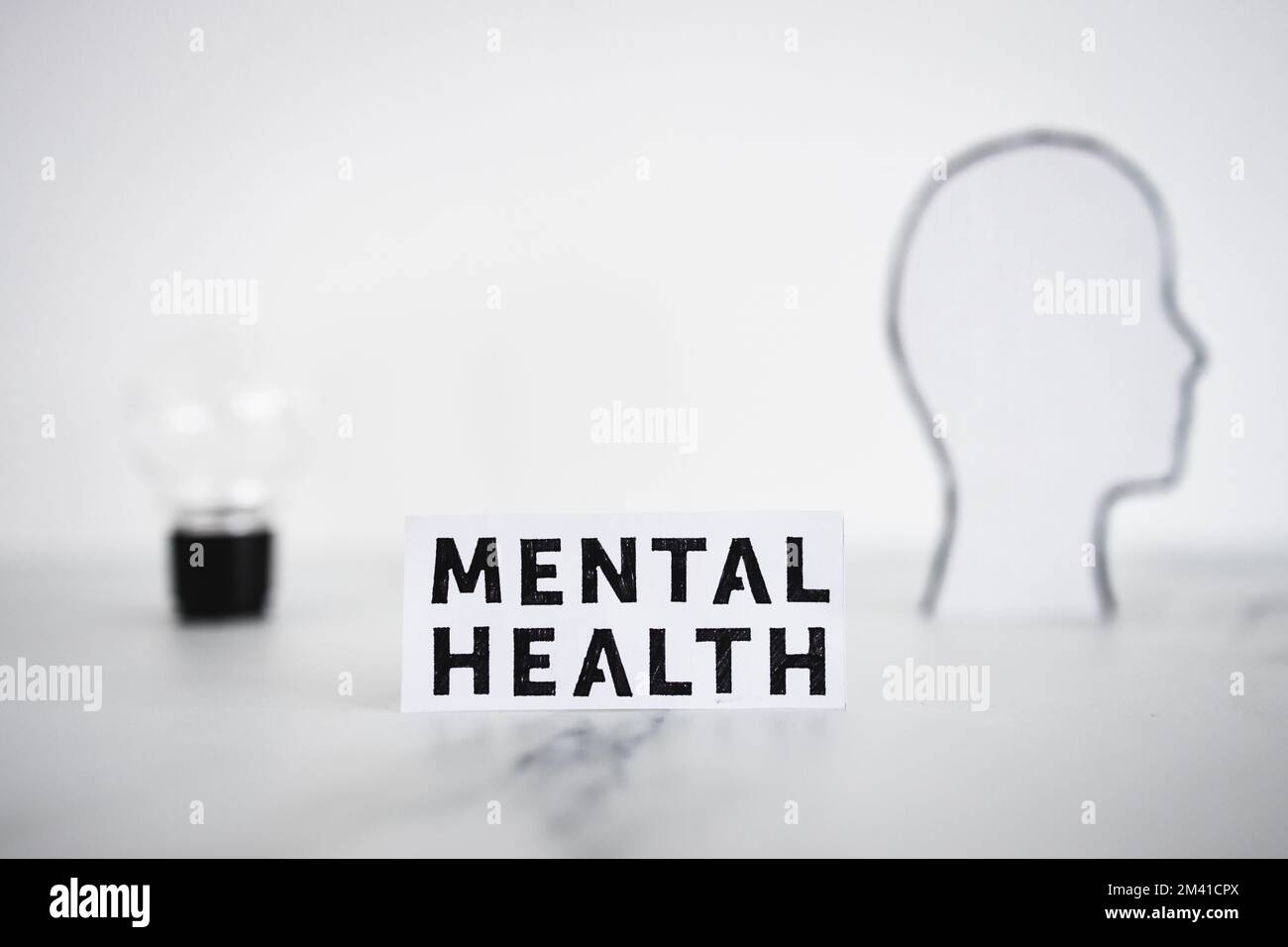 mental health text next to cardboard head with light bulb, psychology