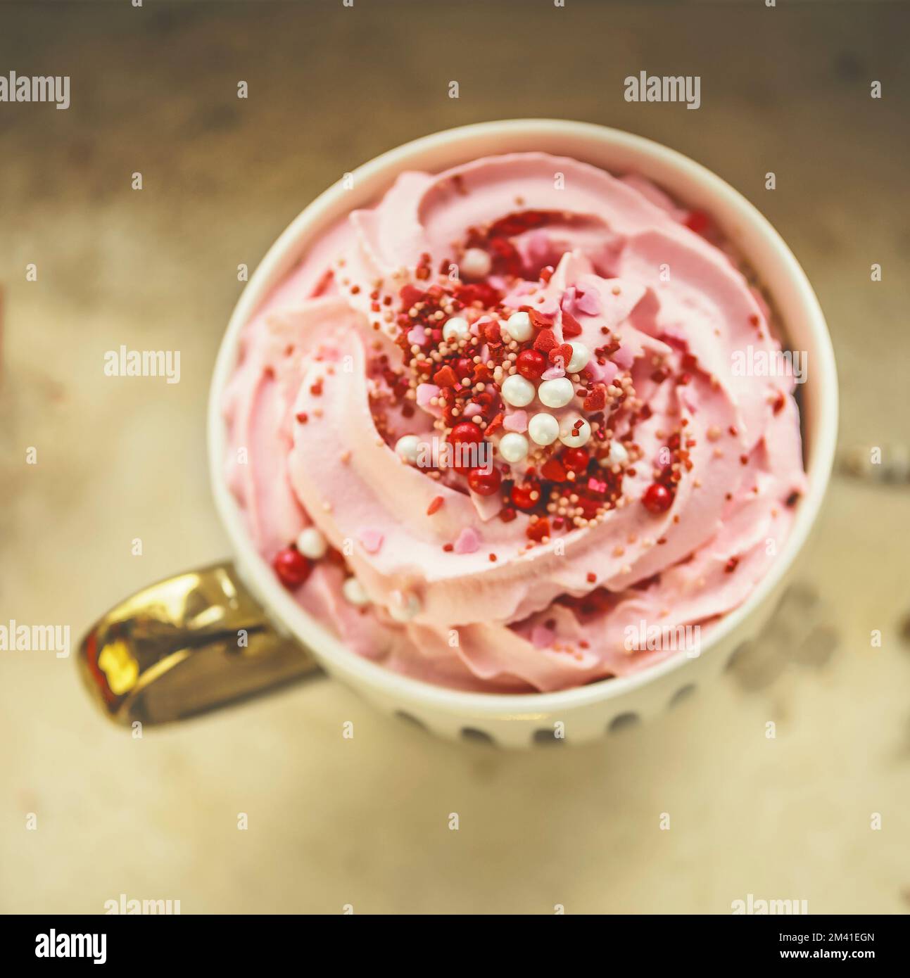 Close up of cup with hot chocolate with pink whipped cream and red sweets. Top view Stock Photo