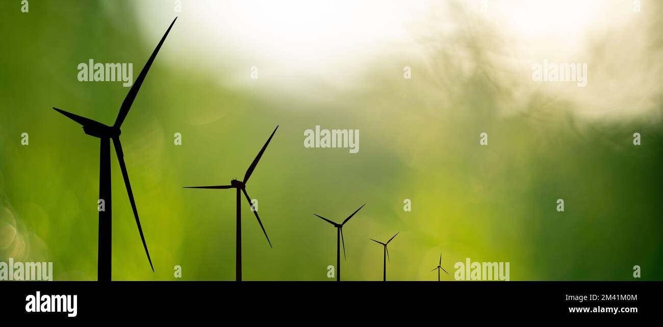 Silhouettes of wind turbines on green background Stock Photo - Alamy
