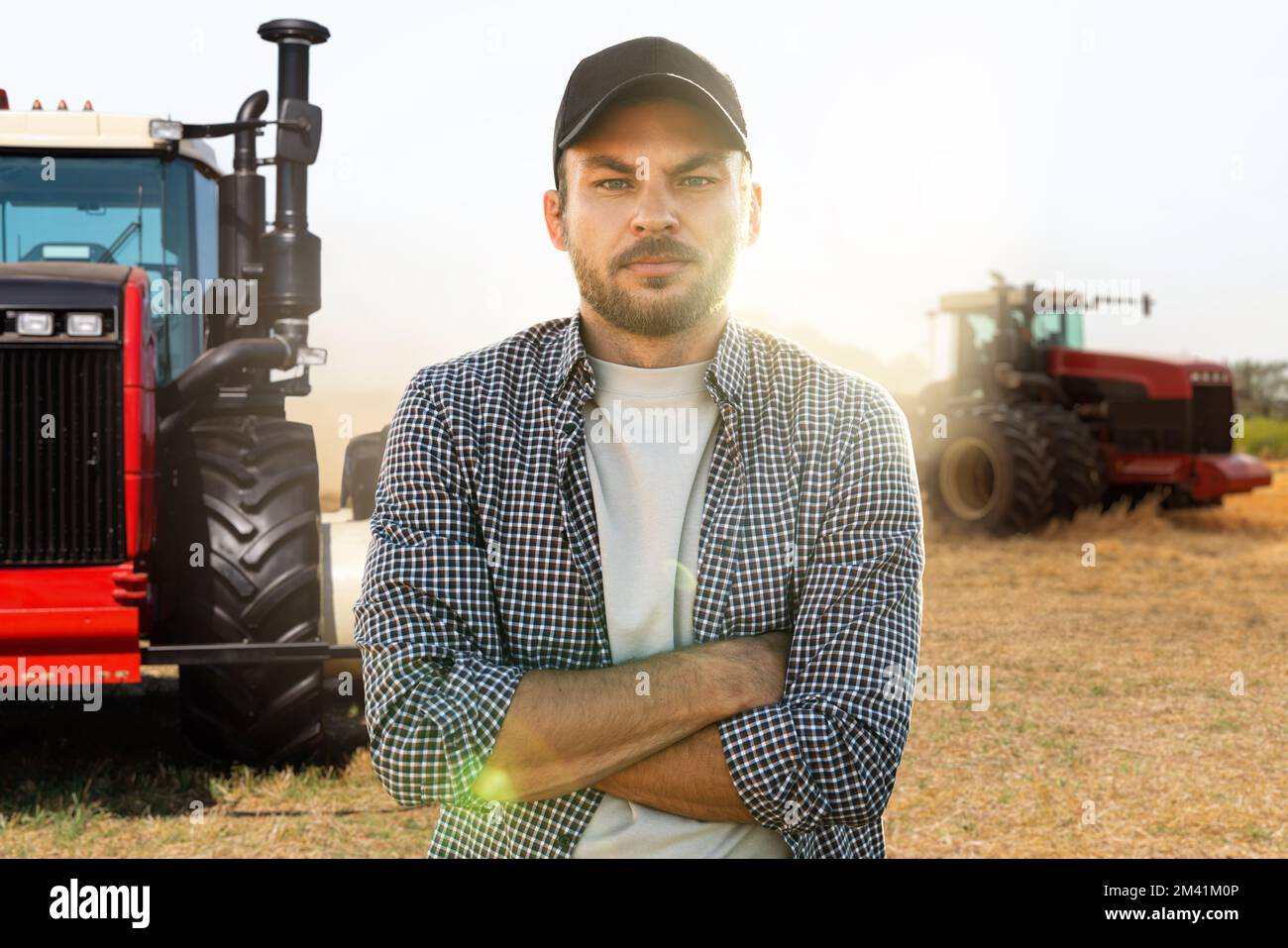 A bearded farmer stands in front of a agricultural tractor Stock Photo ...