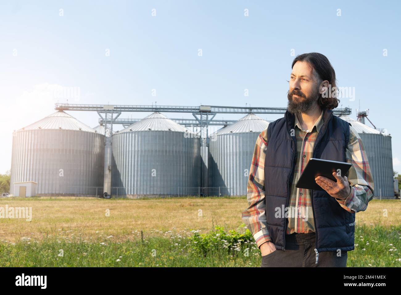 Farmer with digital tablet in front of agricultural silo Stock Photo