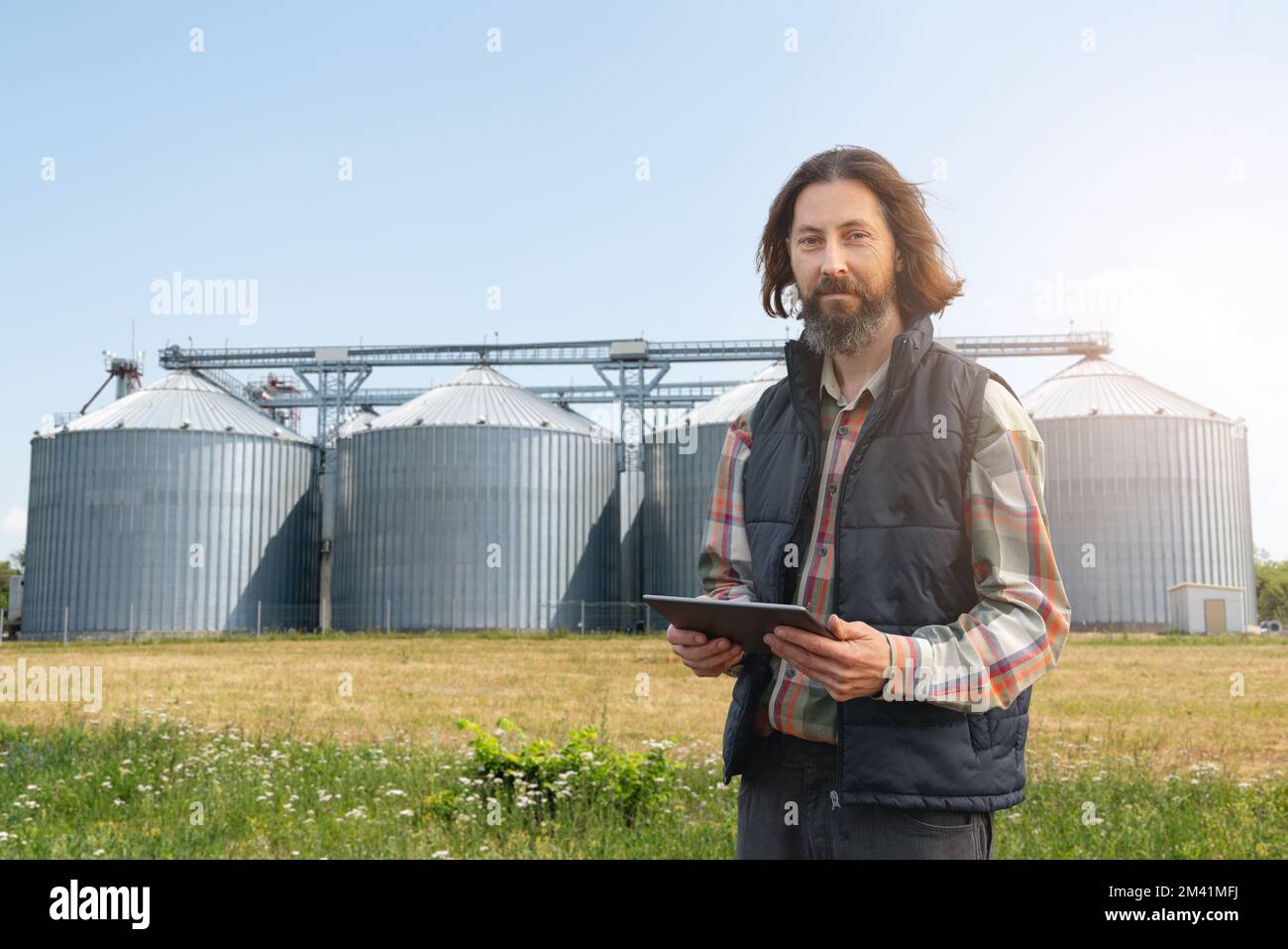 Farmer with digital tablet in front of agricultural silo Stock Photo