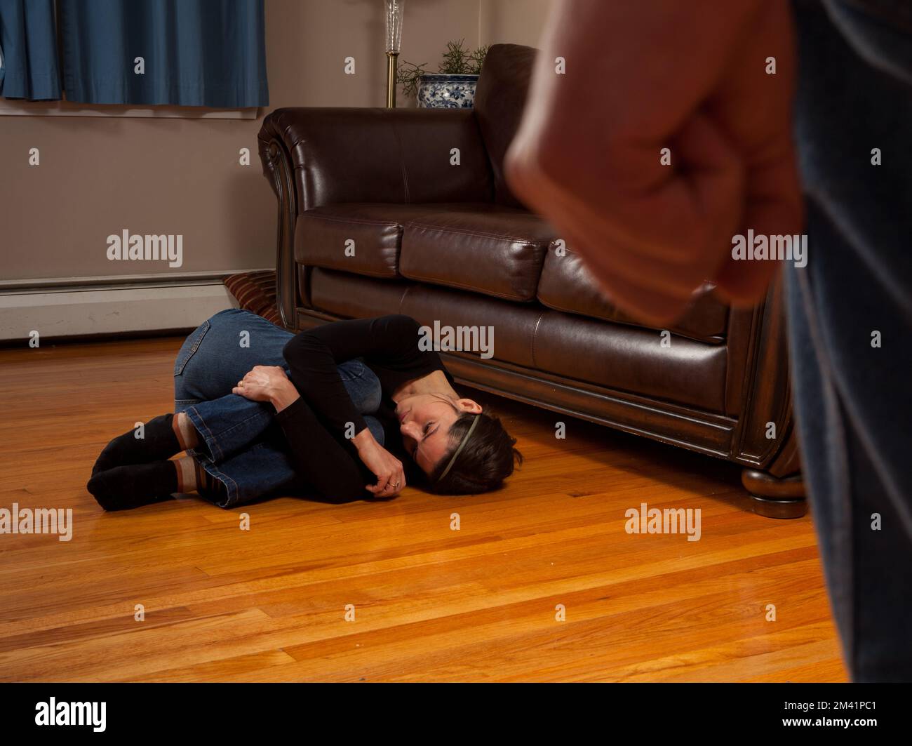 Domestic Violence Awareness - woman curled into fetal position in fear of partner Stock Photo
