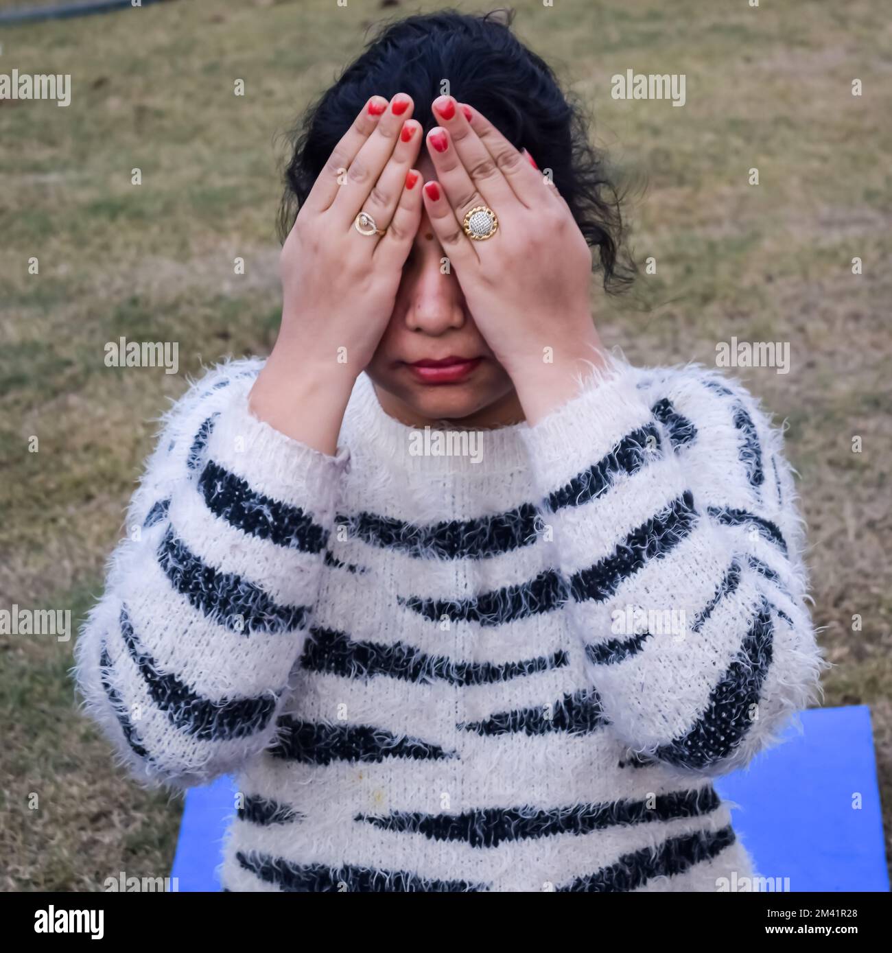 Portrait of gorgeous young Indian woman practicing yoga outdoor in a park. Beautiful girl practice basic yoga pose. Calmness and relax, female happine Stock Photo