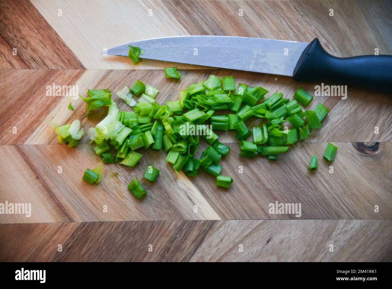 Cut Green onions chives on a cutting board. Dark wooden background. Top view. Stock Photo