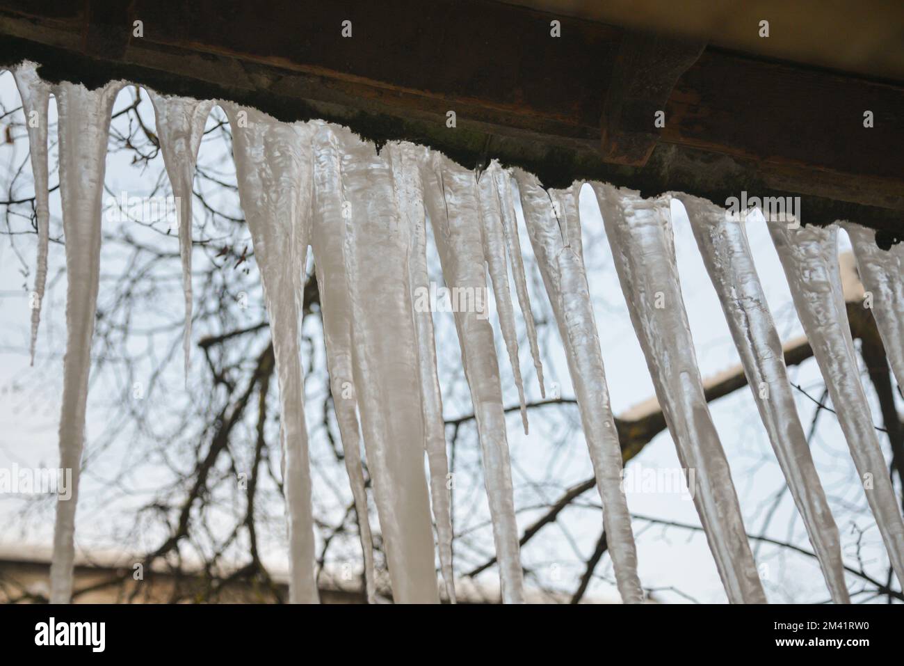 Icicles hanging from the roof against the sky Stock Photo