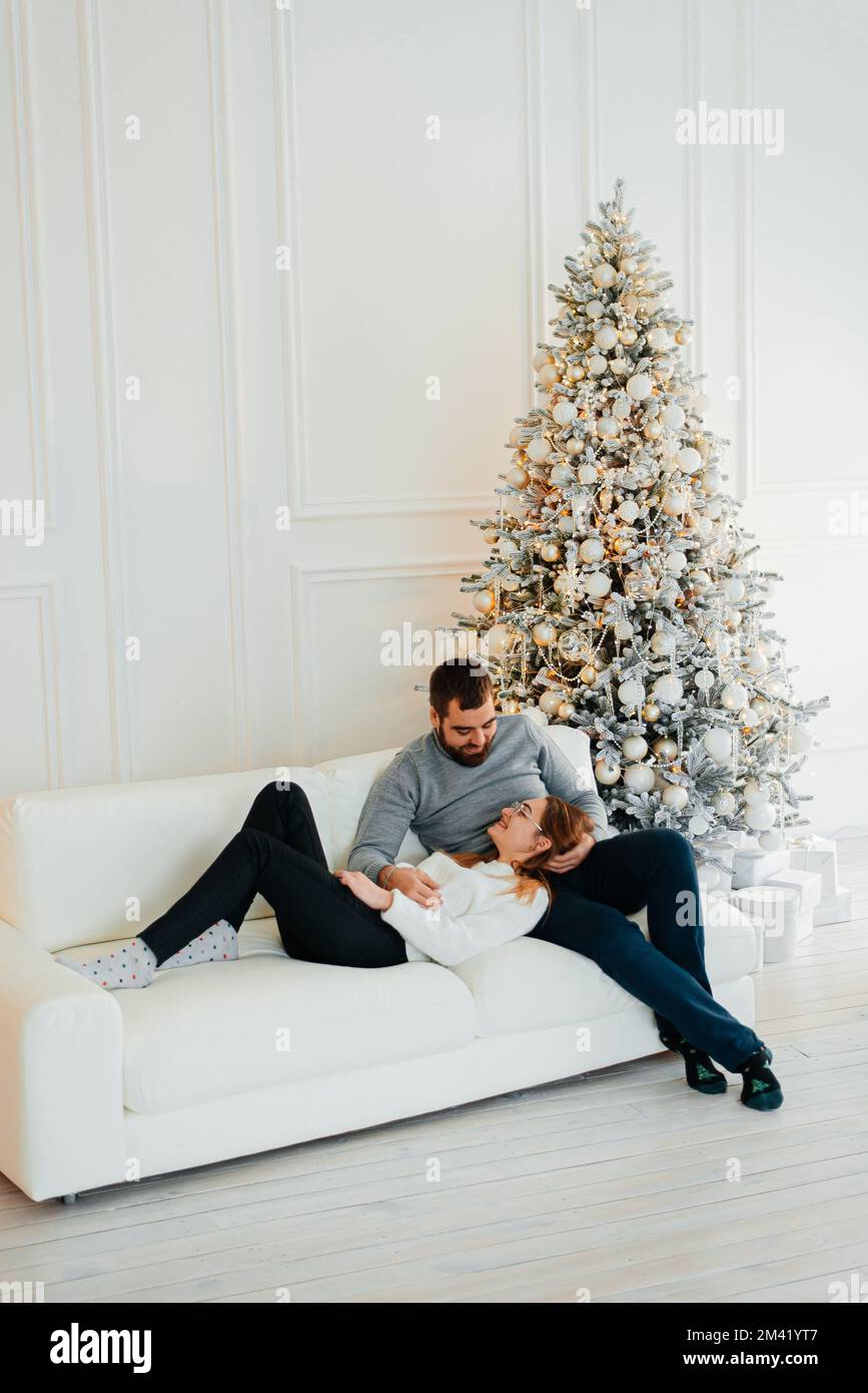 An attractive couple near Christmas tree and hugging. New Years atmosphere. Tender hugs near the Christmas tree of two people Stock Photo