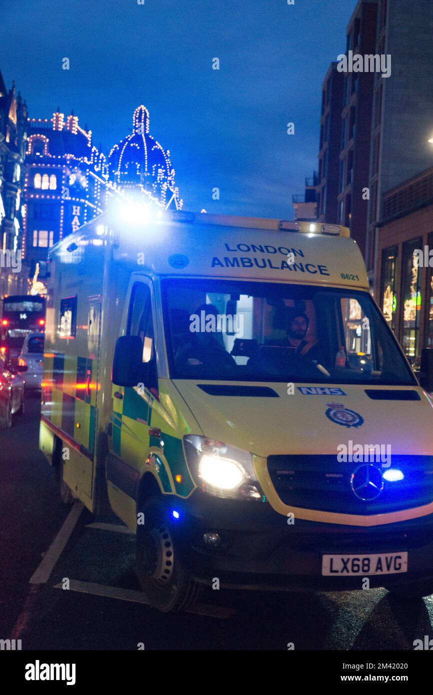 London, UK, 17 December 2022: An emergency ambulance makes it's way through heavy traffic in Knightsbridge, with Christmas lights in the background. In England and Wales ambulance drivers from the GMB, Unison and Unite unions are due to strike on 21 December in a dispute over pay. Anna Watson/Alamy Live News Stock Photo