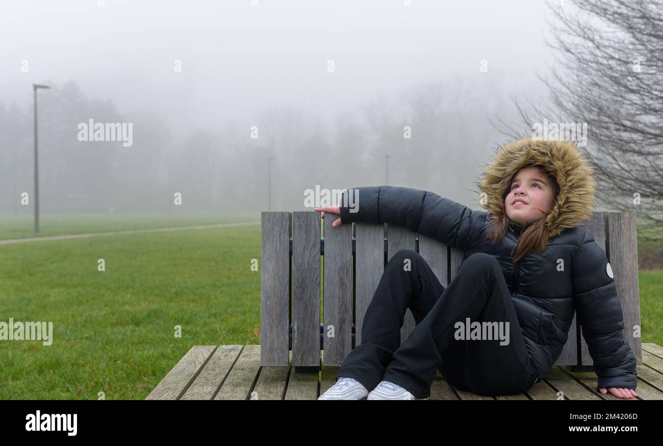 Waiting for snow. Portrait of a teenage girl in the park in January. Winter without snow. Stock Photo