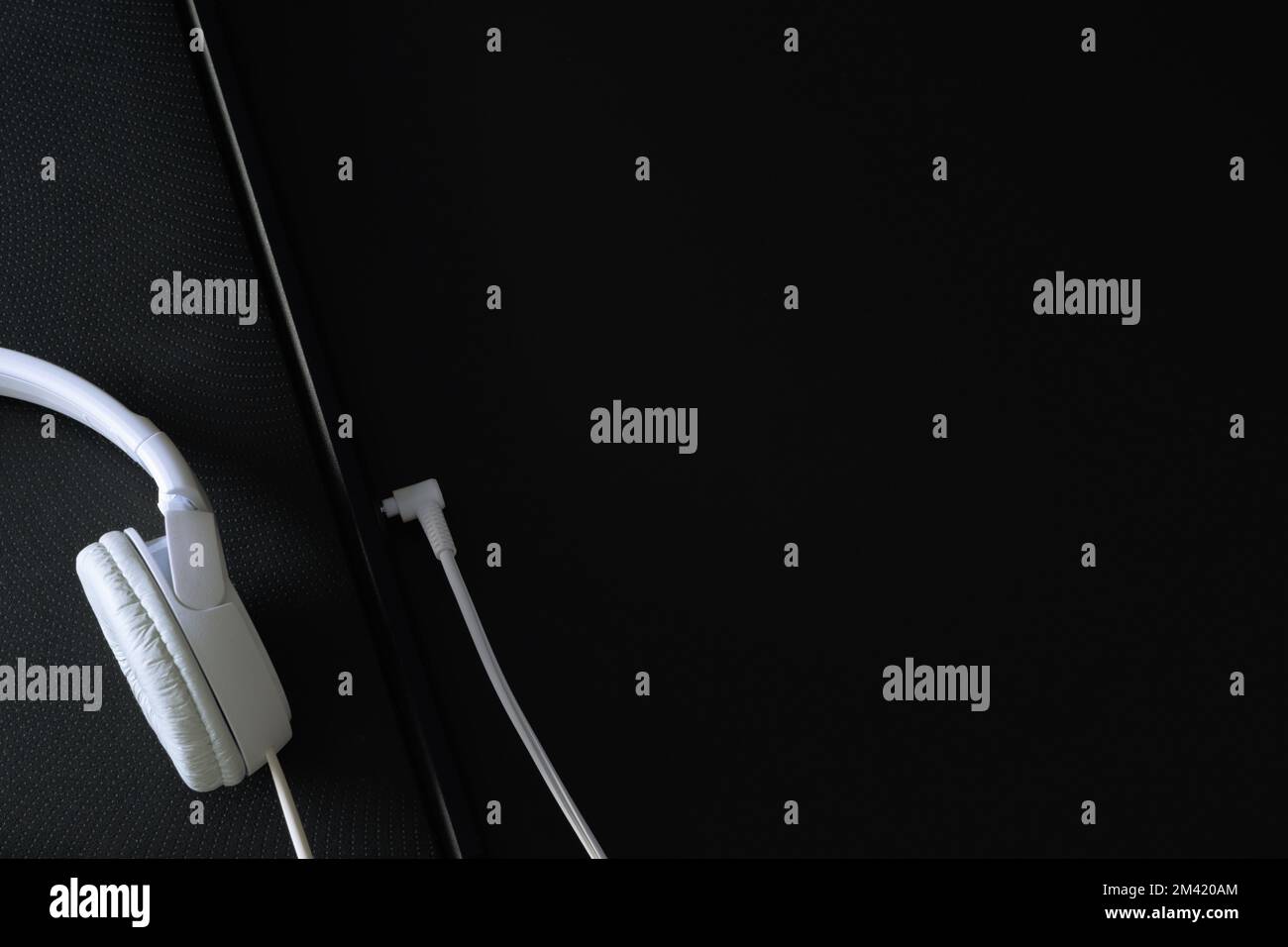 White headphones and part of notebook on a black background. Stock Photo