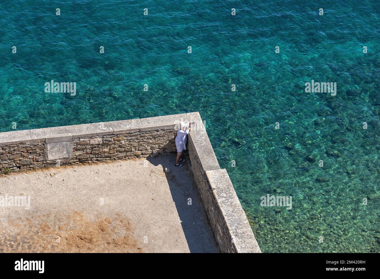 Aerial view of lonely woman tourist taking a picture on terrace overlooking the Adriatic Sea in coastal town of Piran in Slovenia. Stock Photo