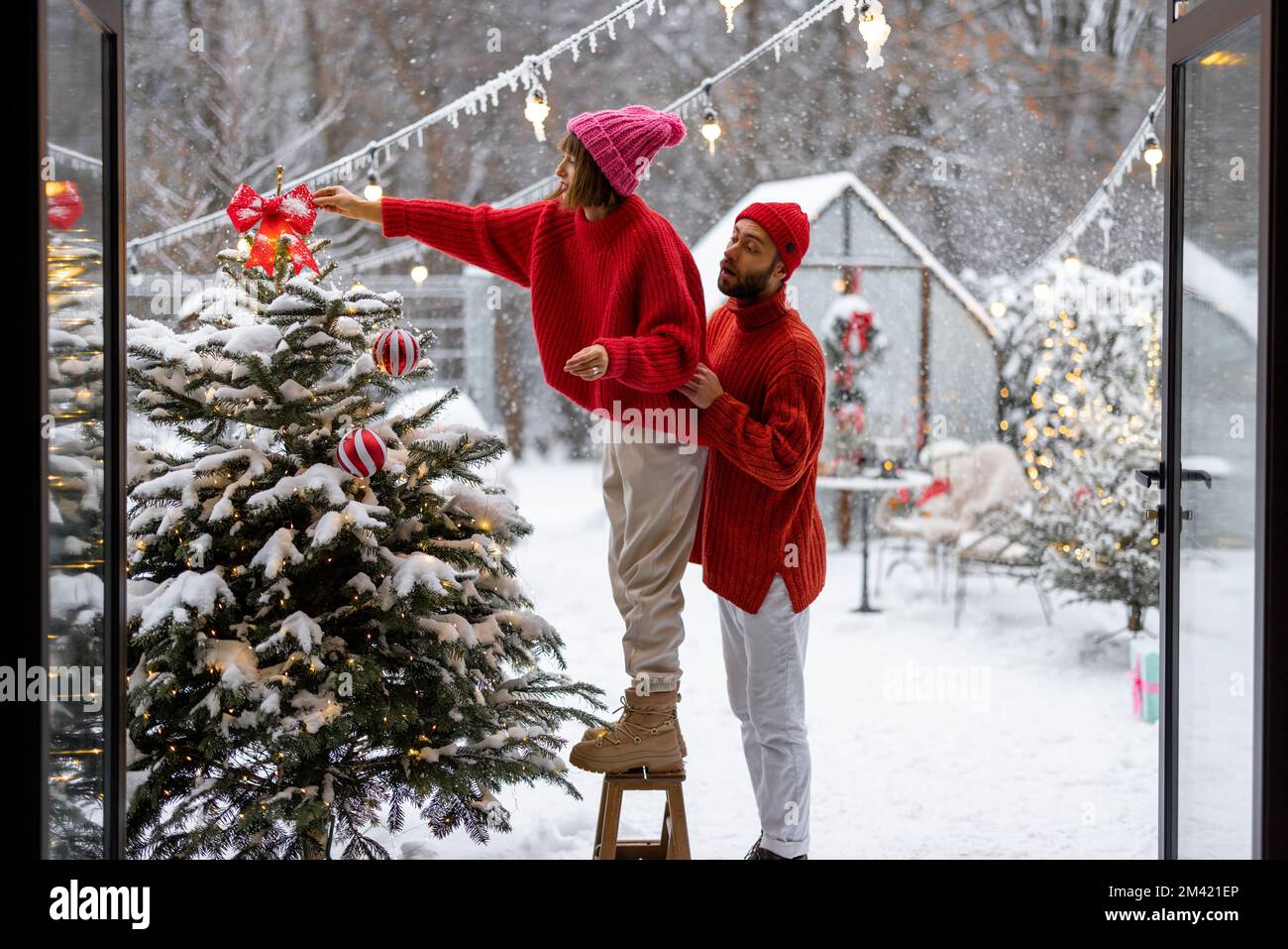 Young couple decorates Christmas tree at backyard Stock Photo