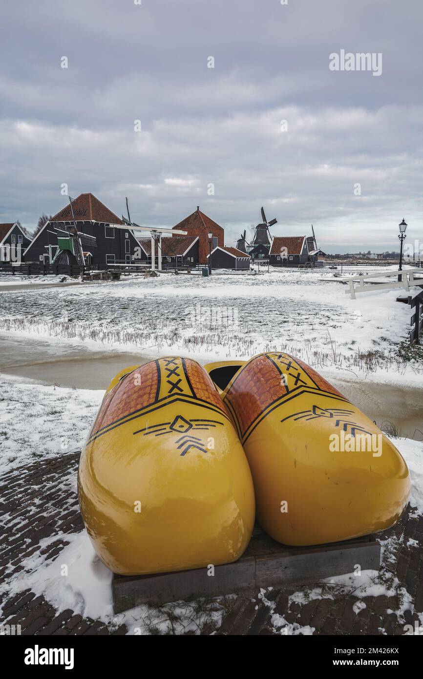 Zaandam, Netherlands, February 10, 2021:The symbol of the Netherlands is a klomp and a windmill against the backdrop of a winter landscape in the smal Stock Photo